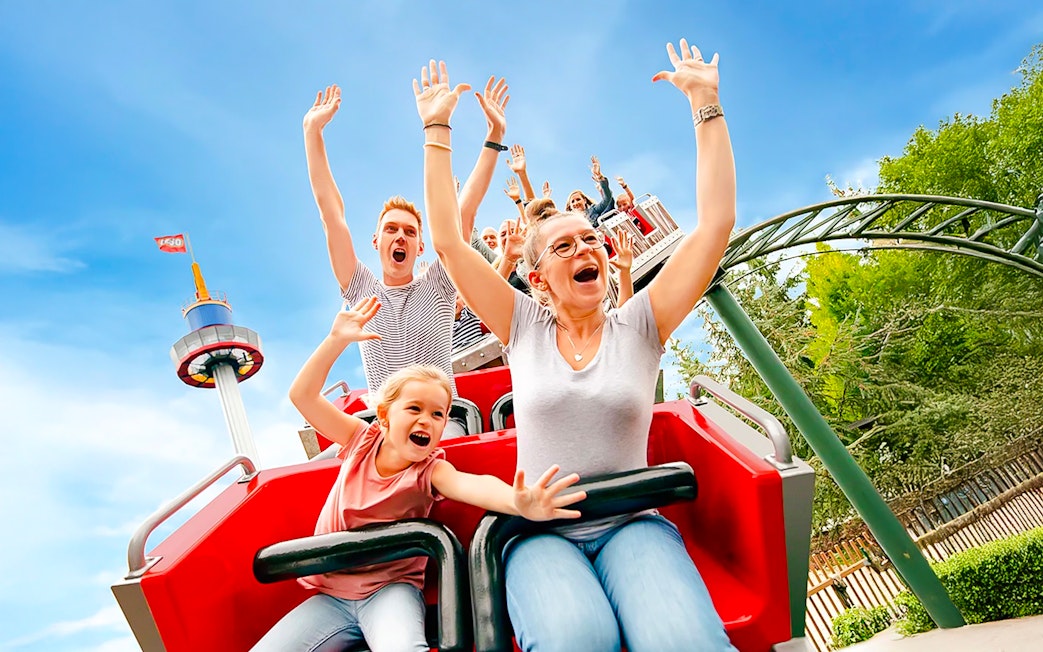 Guests on a roller coaster at LEGOLAND® Deutschland with arms raised in excitement.