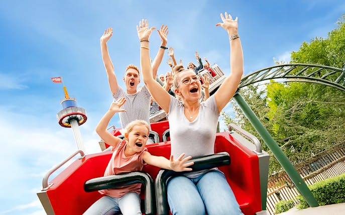 Guests on a roller coaster at LEGOLAND® Deutschland with arms raised in excitement.