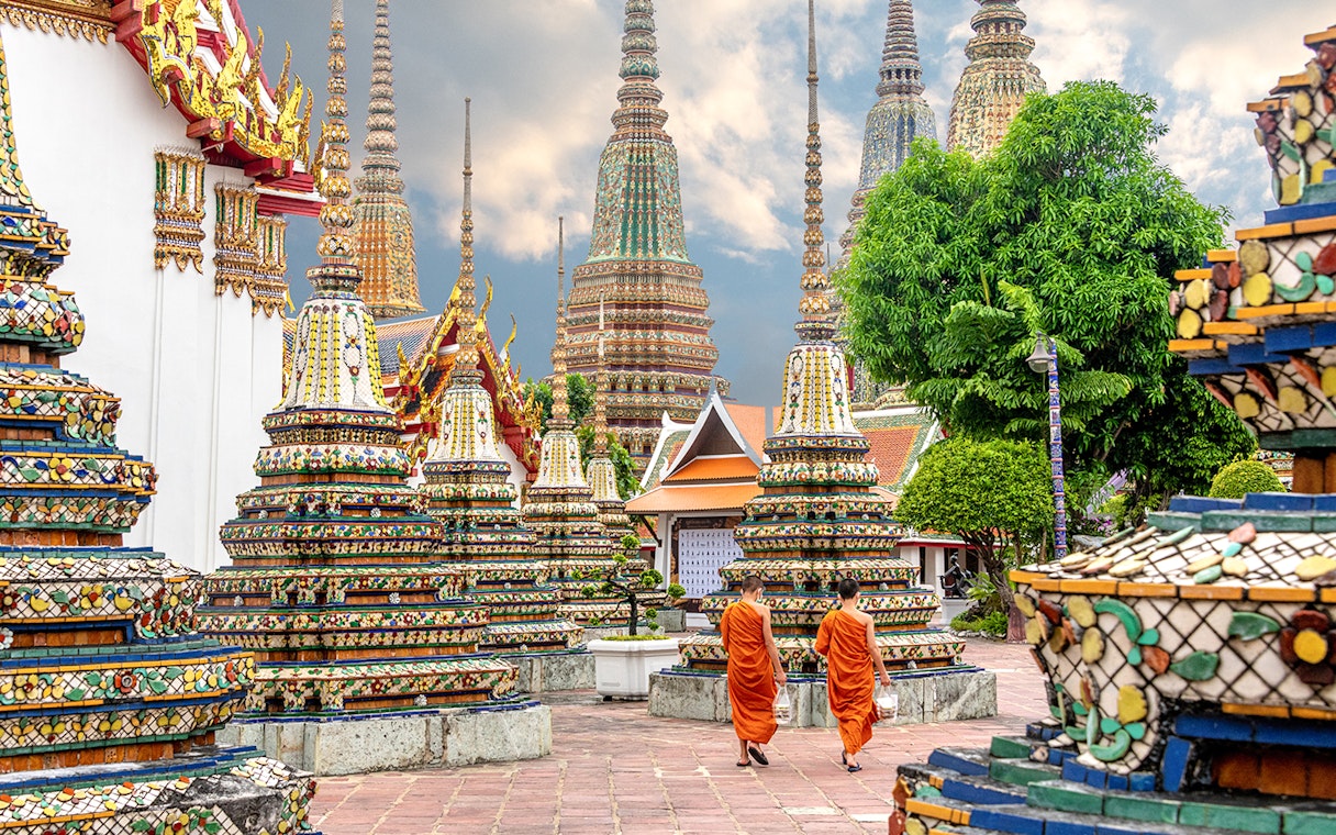 Monks walking among ornate stupas at Wat Pho Temple, Bangkok.