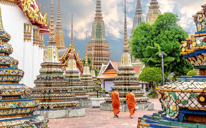 Monks walking among ornate stupas at Wat Pho Temple, Bangkok.