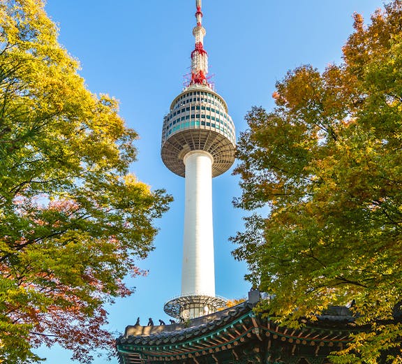 Namsan Seoul Tower rising above colorful autumn trees in Seoul, South Korea.