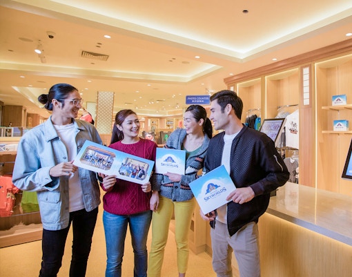 Visitors holding photos at Genting SkyWorlds theme park photo counter.