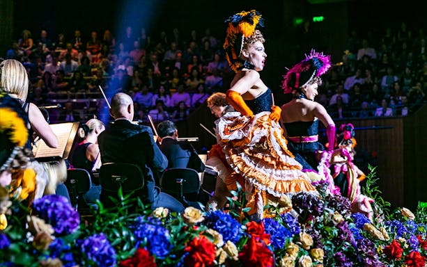 Performers in vibrant costumes at NYE Opera Gala, Sydney Opera House, with orchestra and audience.