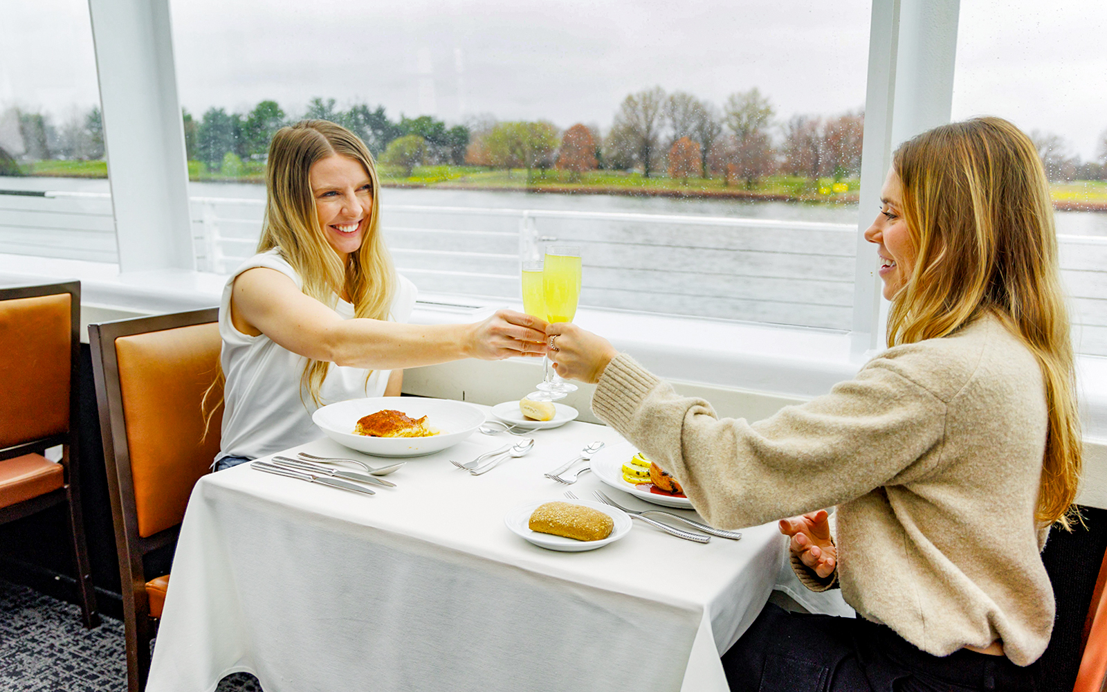 Two people toasting with drinks on a New York Signature Dinner Cruise.