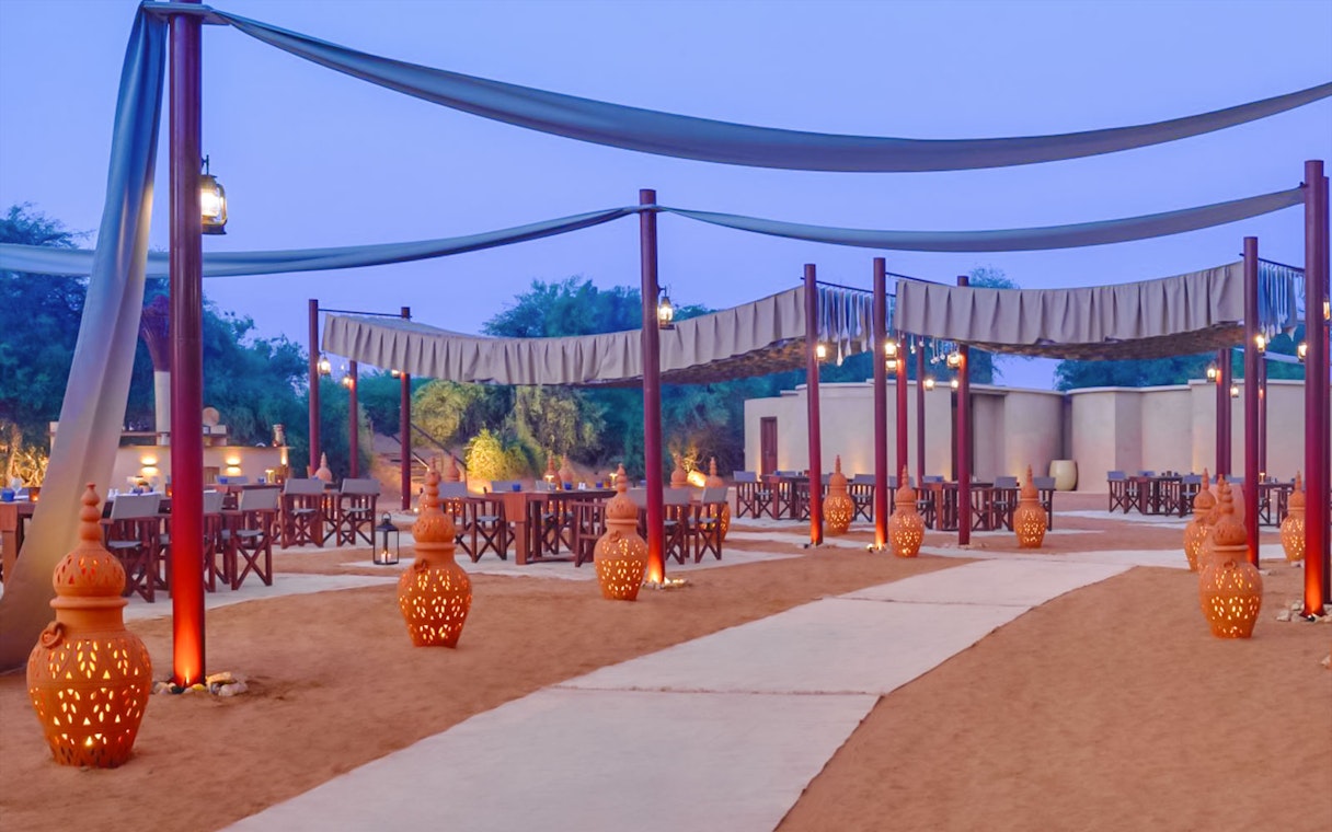Desert dining setup with lanterns and tables at The Nomad Garden.