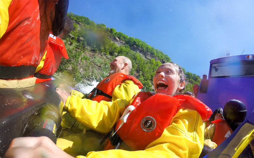 Guests enjoying Whirlpool Jet Boat Tour in Niagara Gorge, Canada, wearing life jackets.