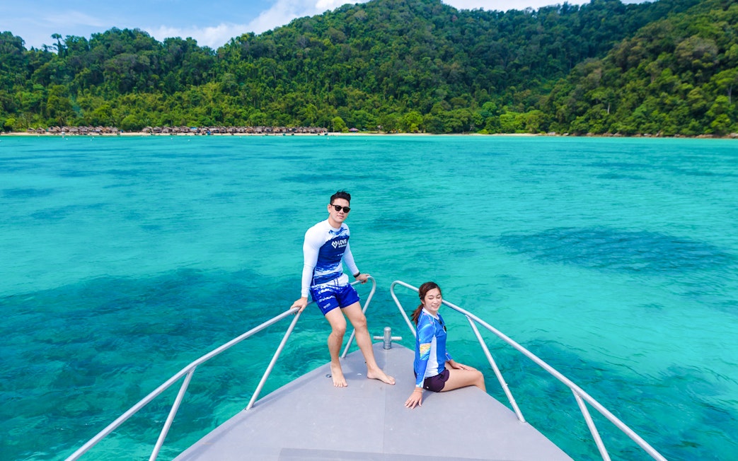 Couple on speedboat bow with Surin Islands' turquoise waters in background.