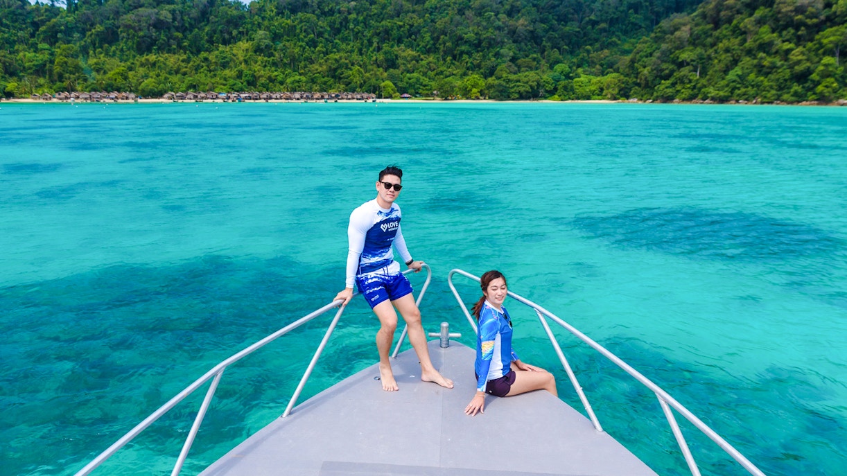 Couple on speedboat bow with Surin Islands' turquoise waters in background.