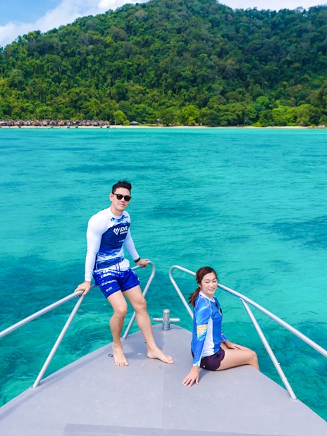 Couple on speedboat bow with Surin Islands' turquoise waters in background.