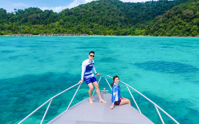 Couple on speedboat bow with Surin Islands' turquoise waters in background.
