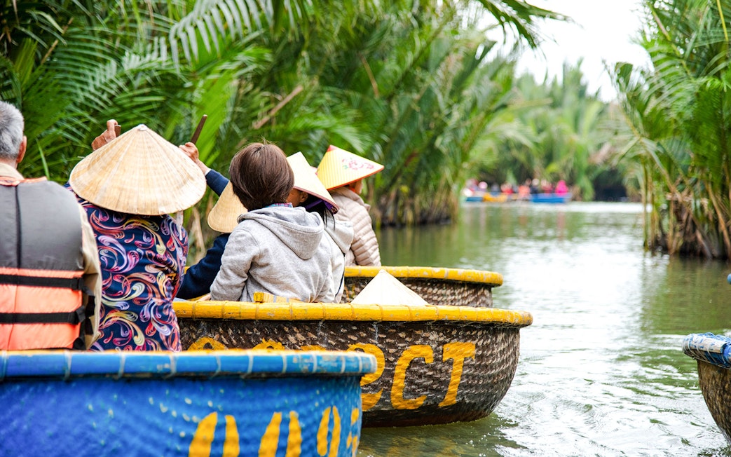 Tourists riding coconut basket boats through lush palm-lined waterways.