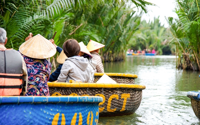 Tourists riding coconut basket boats through lush palm-lined waterways.