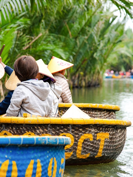 Tourists riding coconut basket boats through lush palm-lined waterways.