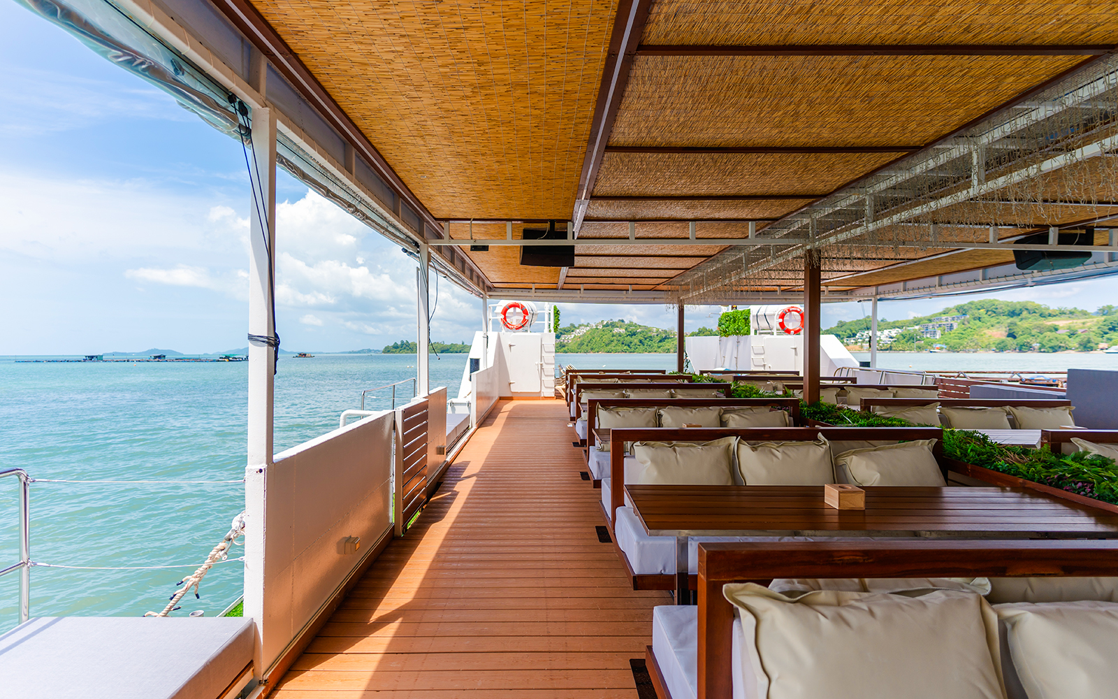 Cruise ship deck with seating area overlooking the ocean and distant islands.