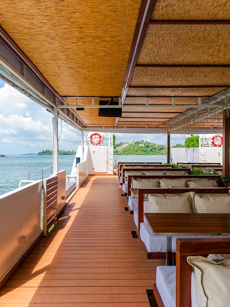 Cruise ship deck with seating area overlooking the ocean and distant islands.