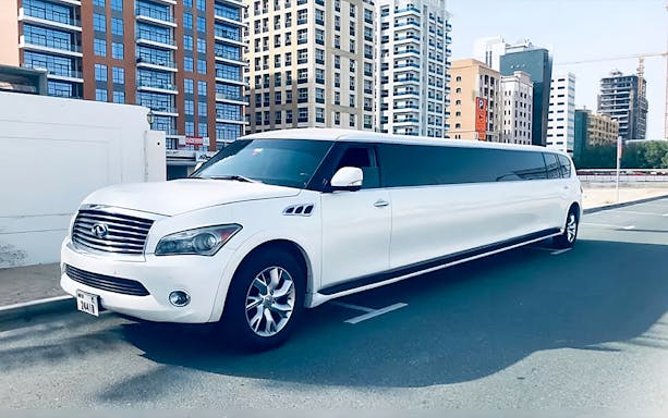 White limousine parked on a street in Dubai with modern buildings in the background.