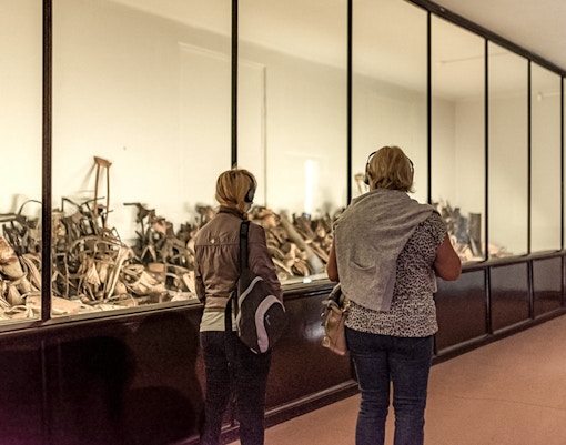 Visitors viewing personal artifacts at Auschwitz museum exhibit.