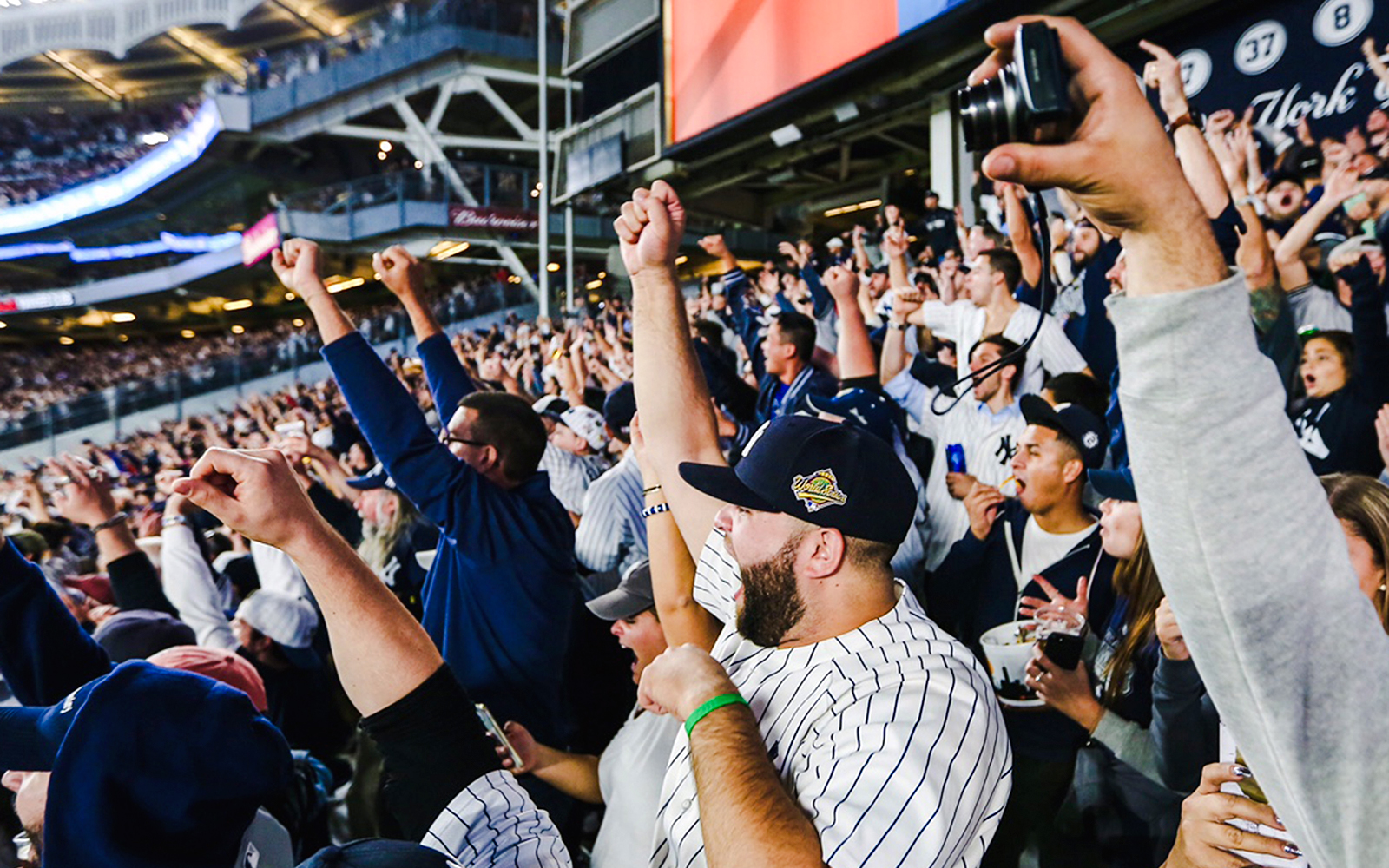 Fans celebrating at a Yankees game in a packed stadium.