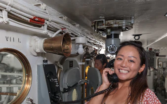 Visitor using phone on Battleship IOWA guided gun tour.