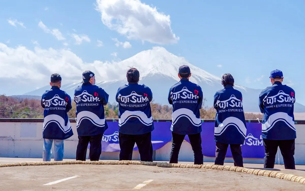 Sumo wrestlers in traditional attire facing Mount Fuji, Yamanashi Fuji Sumo Show & Experience.