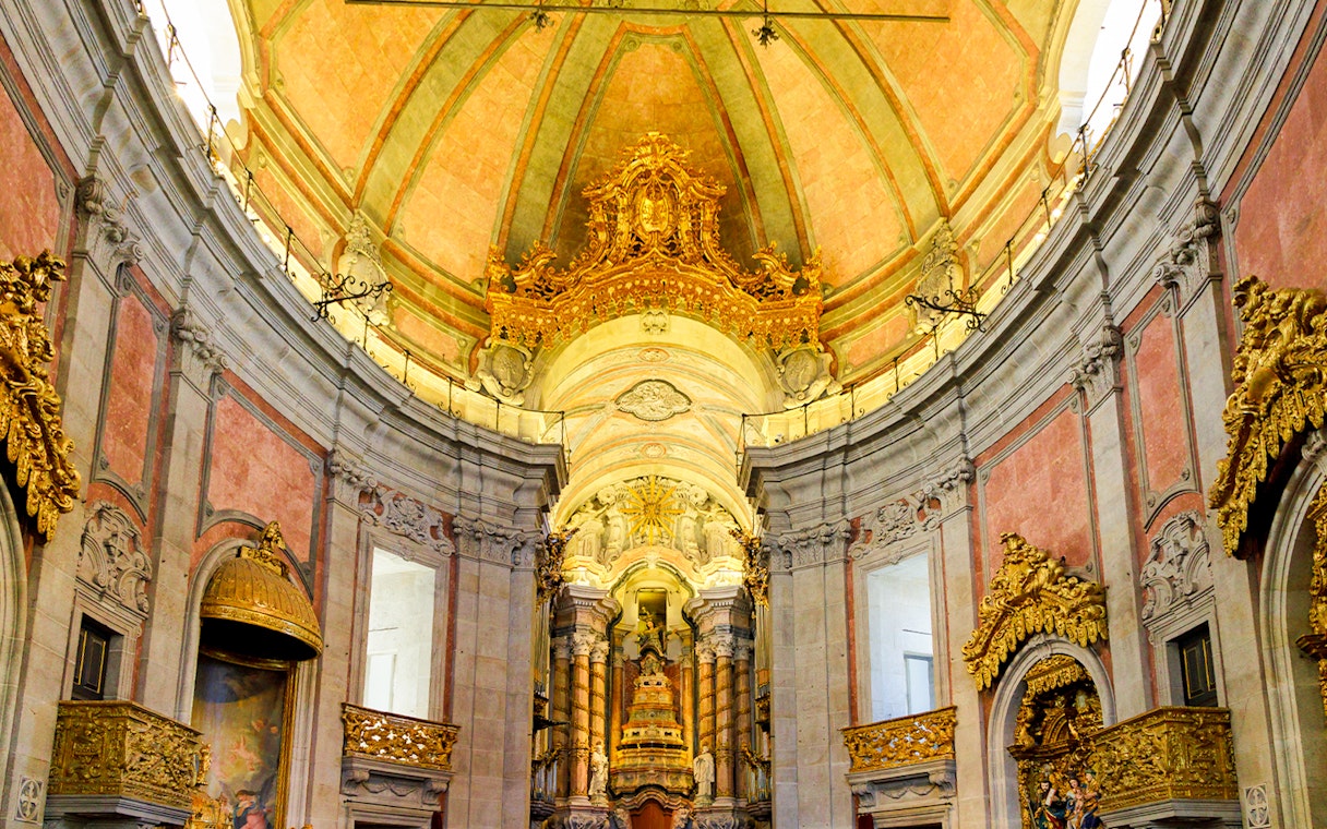 Interior of Clérigos Church in Porto, Portugal, showcasing Baroque architecture and ornate gold details.
