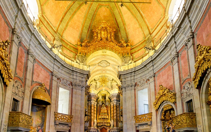 Interior of Clérigos Church in Porto, Portugal, showcasing Baroque architecture and ornate gold details.