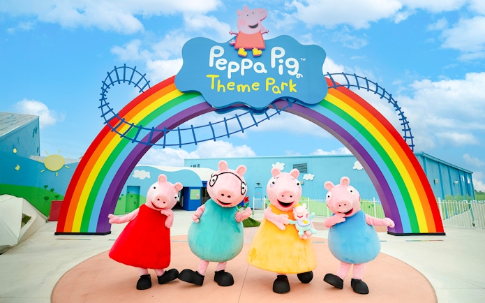 Peppa Pig characters under rainbow arch at Peppa Pig Theme Park, Florida.