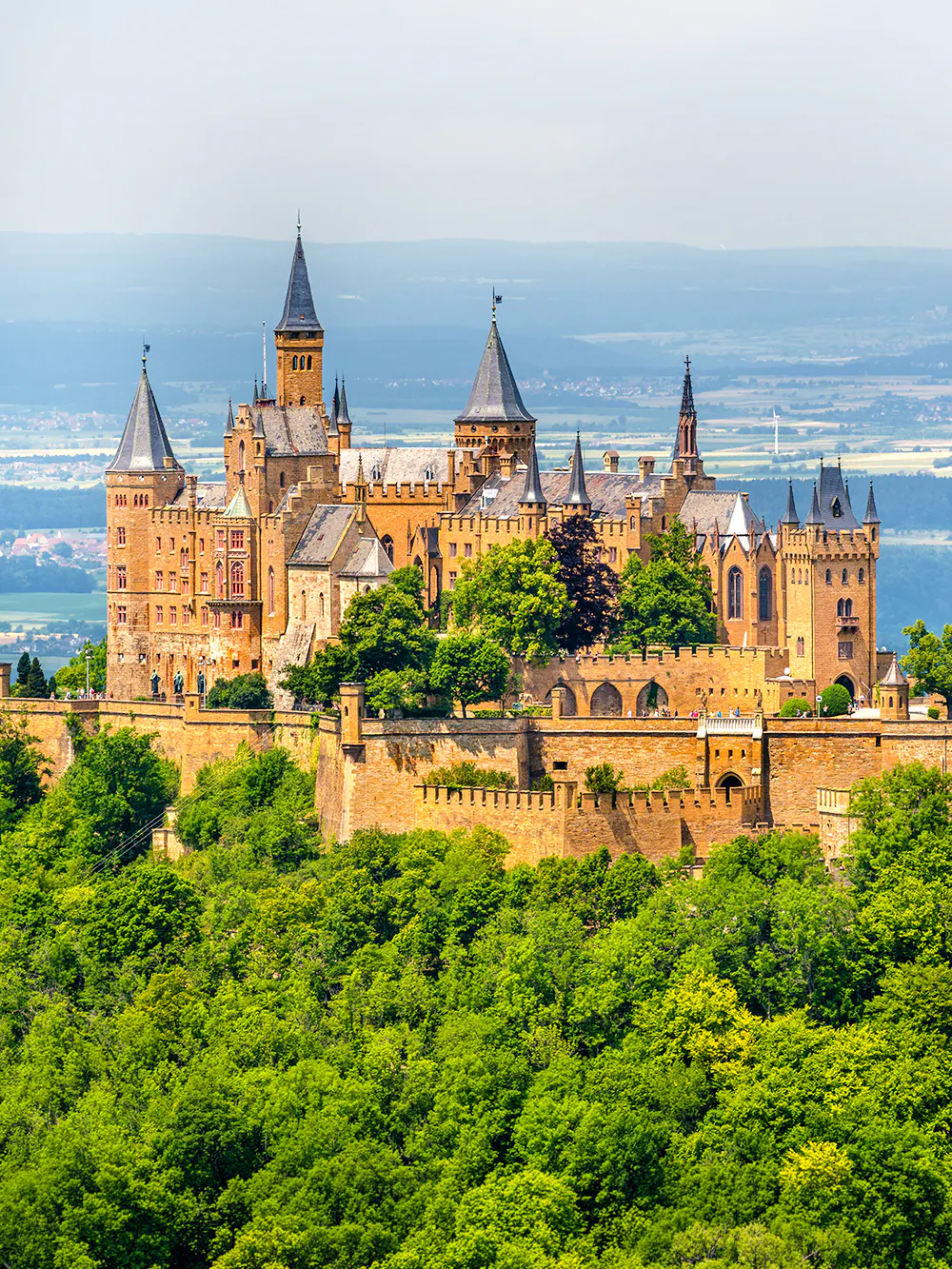 Hohenzollern Castle atop a forested hill in the Swabian Alps, Baden-Württemberg, Germany.