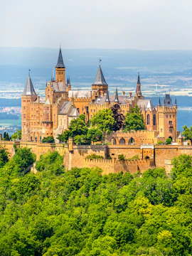 Hohenzollern Castle atop a forested hill in the Swabian Alps, Baden-Württemberg, Germany.