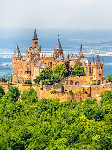 Hohenzollern Castle atop a forested hill in the Swabian Alps, Baden-Württemberg, Germany.