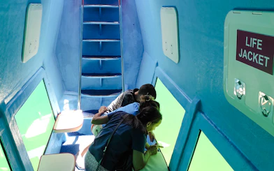 Underwater submarine interior with tourists viewing Boka Bay, Kotor through windows.