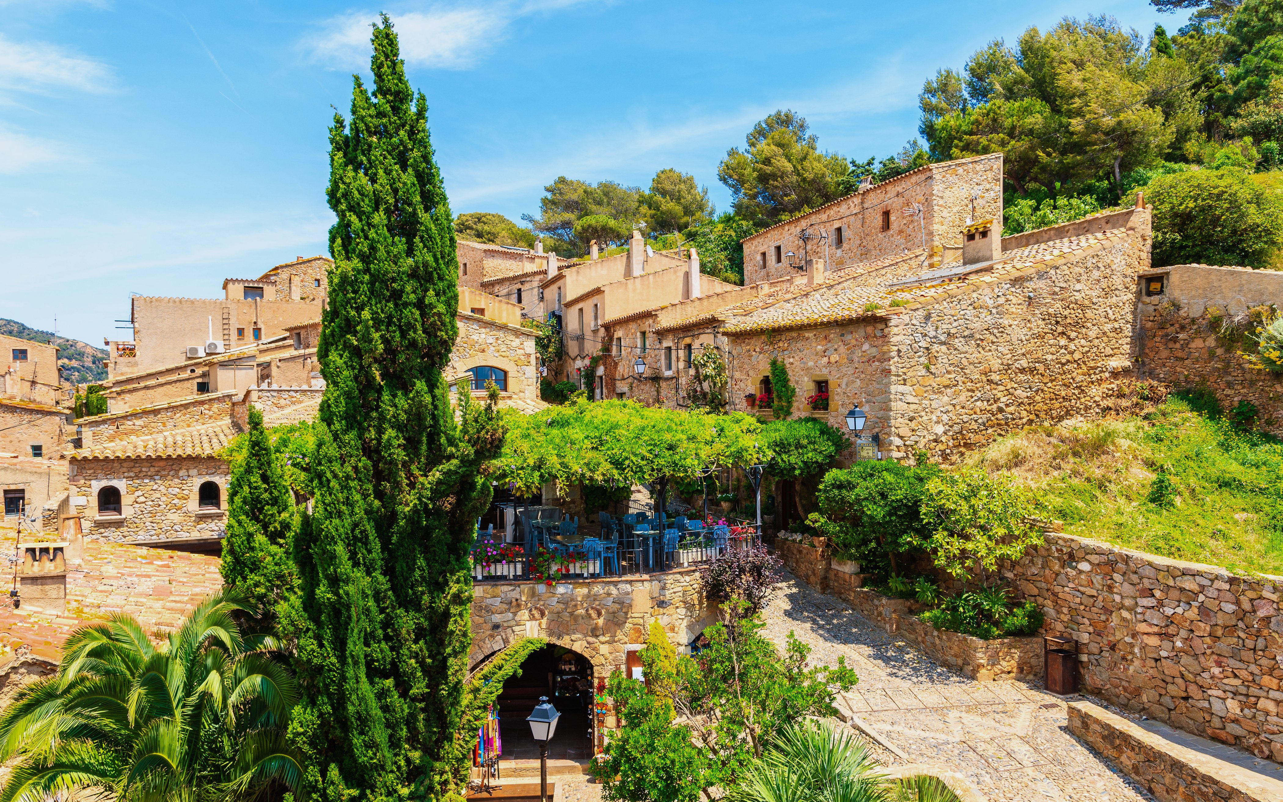 Restaurant terrace among stone houses in Tossa de Mar's old town, Costa Brava, Spain.