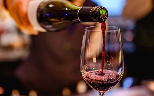 Pouring red wine into a glass at a wine tasting event.