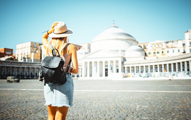 Tourist with backpack at Piazza Del Plebiscito, Naples, facing the basilica.