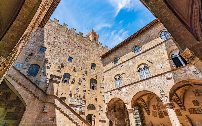 Museo del Bargello courtyard with stone walls and arched windows in Florence, Italy.