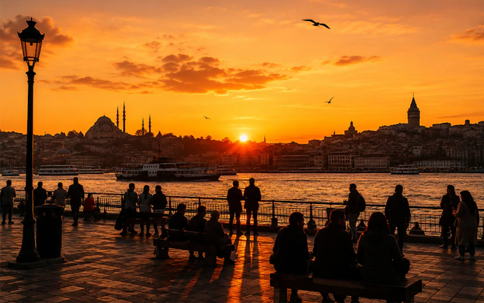 Galata Tower and Istanbul skyline at sunset with people by the waterfront.