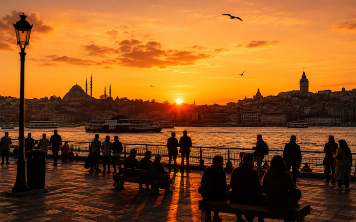 Galata Tower and Istanbul skyline at sunset with people by the waterfront.