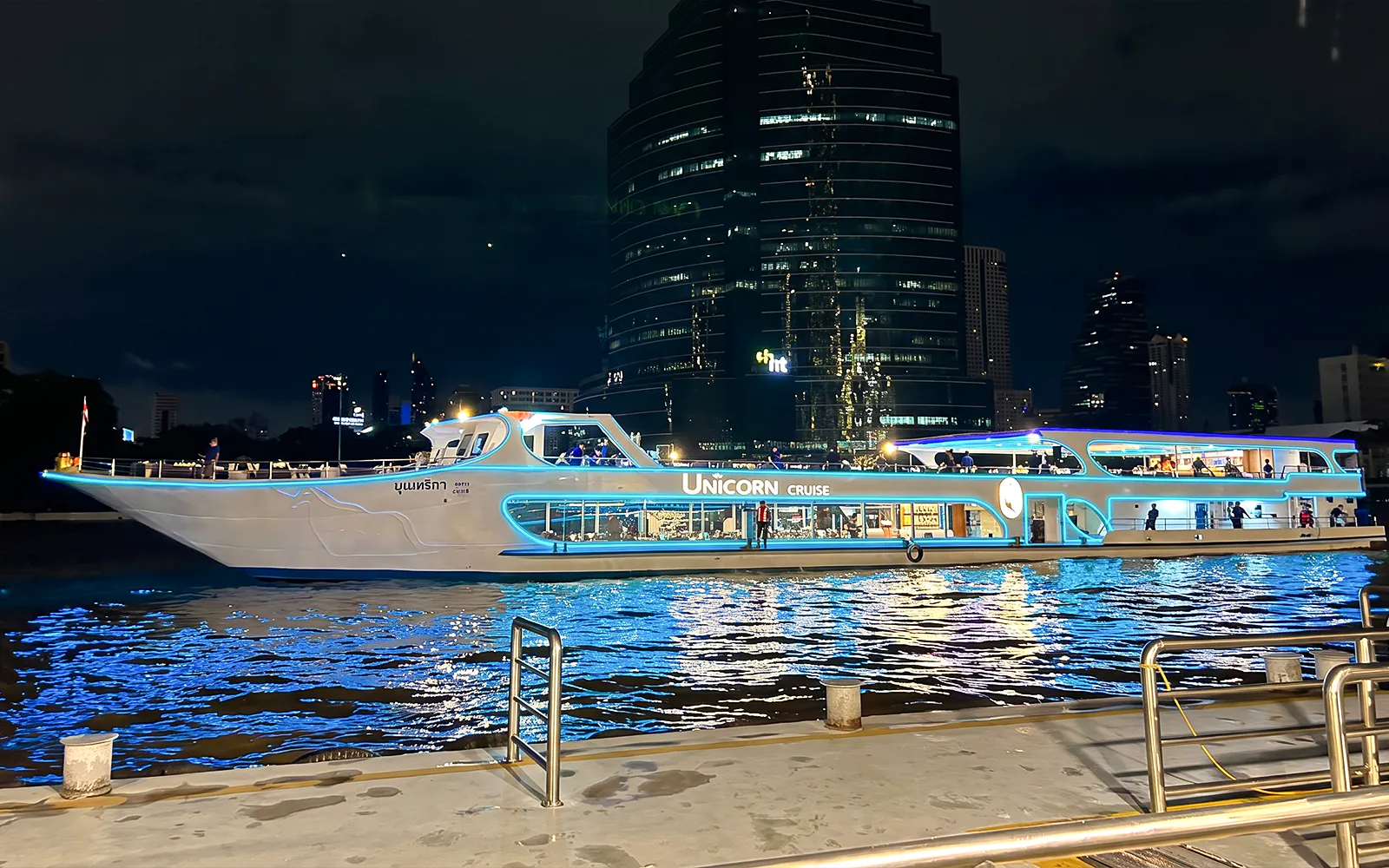 Unicorn Dinner Cruise boat illuminated at night on the Chao Phraya River in Bangkok.