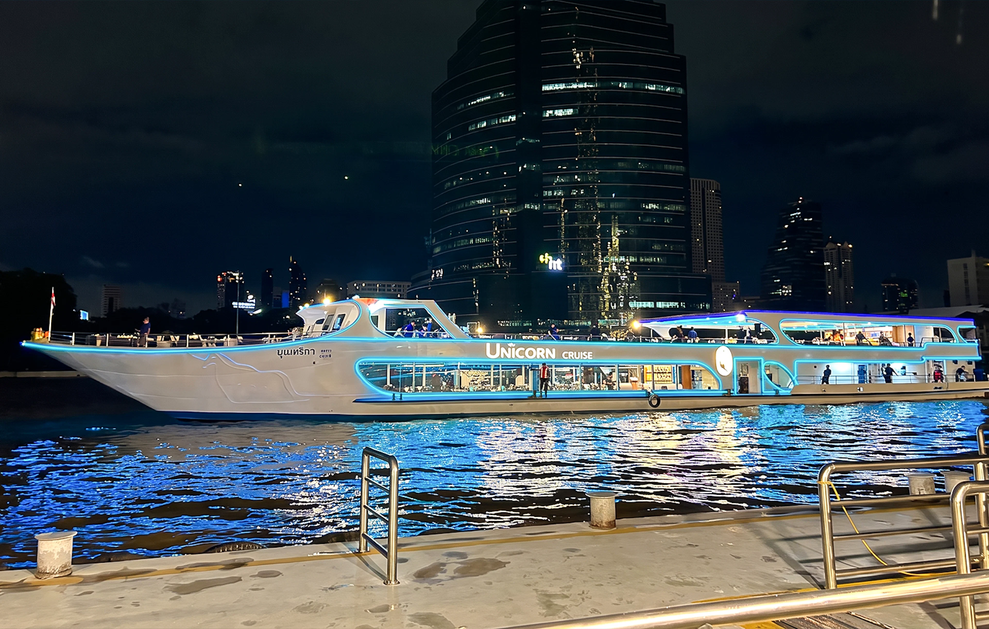 Unicorn Dinner Cruise boat illuminated at night on the Chao Phraya River in Bangkok.