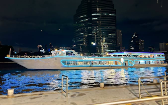 Unicorn Dinner Cruise boat illuminated at night on the Chao Phraya River in Bangkok.