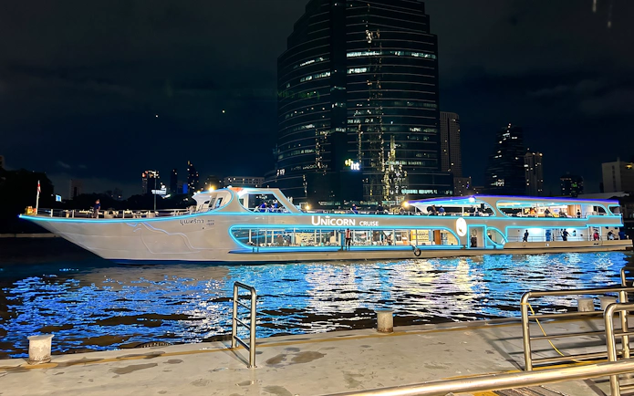 Unicorn Dinner Cruise boat illuminated at night on the Chao Phraya River in Bangkok.