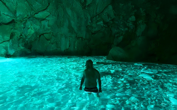 Person wading in the illuminated waters of Blue Caves, Albania.