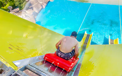 Man on a yellow water slide at Aquopolis Villanueva de la Cañada.