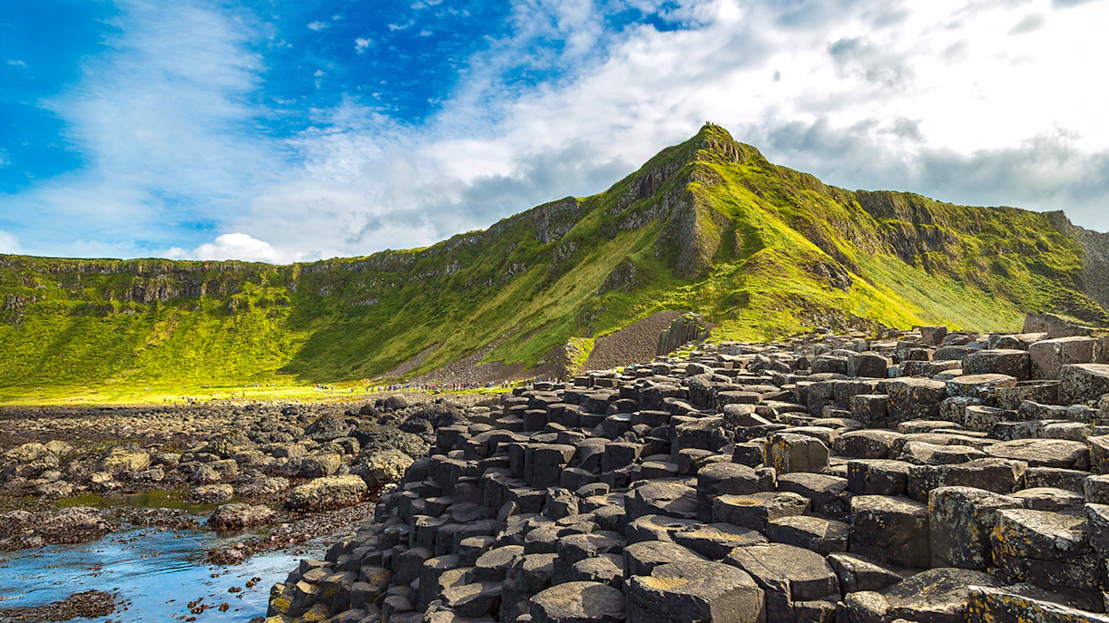 Giant's Causeway basalt columns with green cliffs in Northern Ireland.