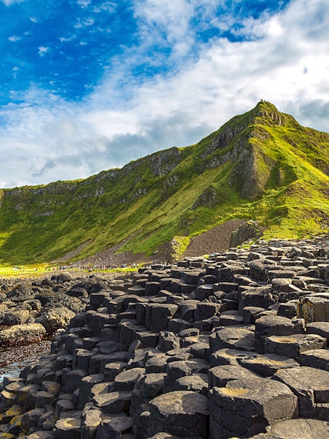 Giant's Causeway basalt columns with green cliffs in Northern Ireland.