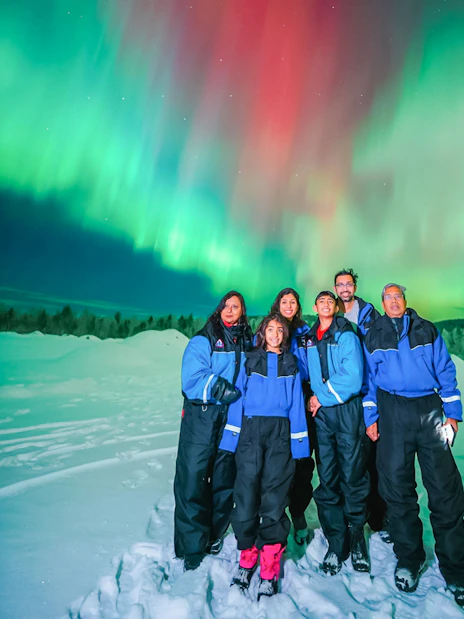 Guests on Northern Lights Chase Bus Tour in Rovaniemi under aurora borealis.