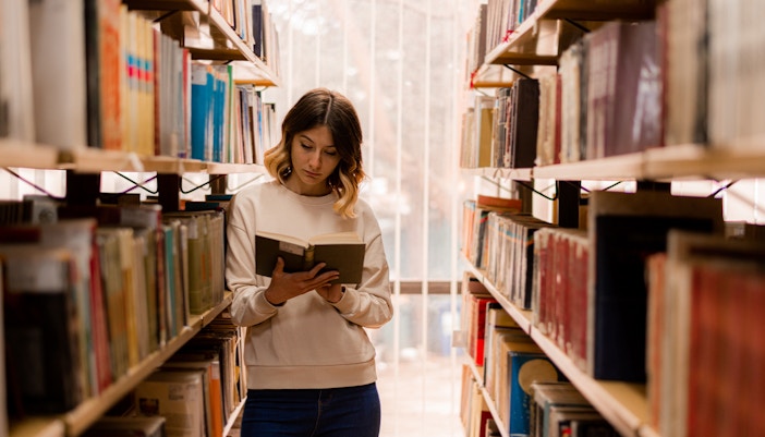 Tourist engrossed in reading a book in a grand library during a city tour