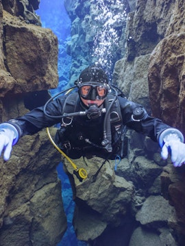 Snorkeler exploring Silfra's clear waters between tectonic plates in Iceland.