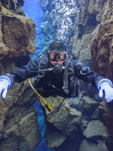 Snorkeler exploring Silfra's clear waters between tectonic plates in Iceland.