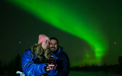Couple enjoying Northern Lights in Rovaniemi, holding a ring box.